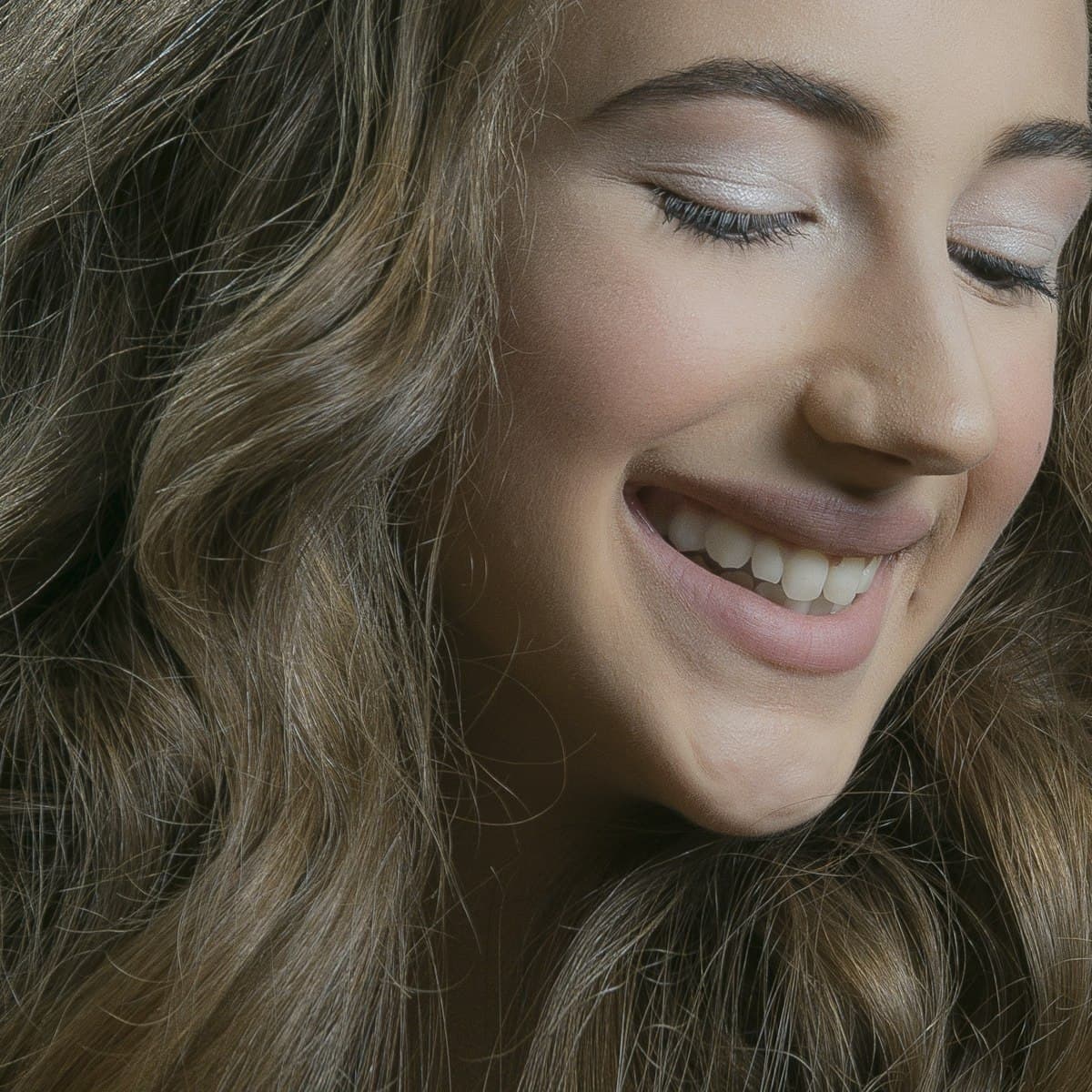 Warm close-up portrait of a woman laughing with a confident, natural smile