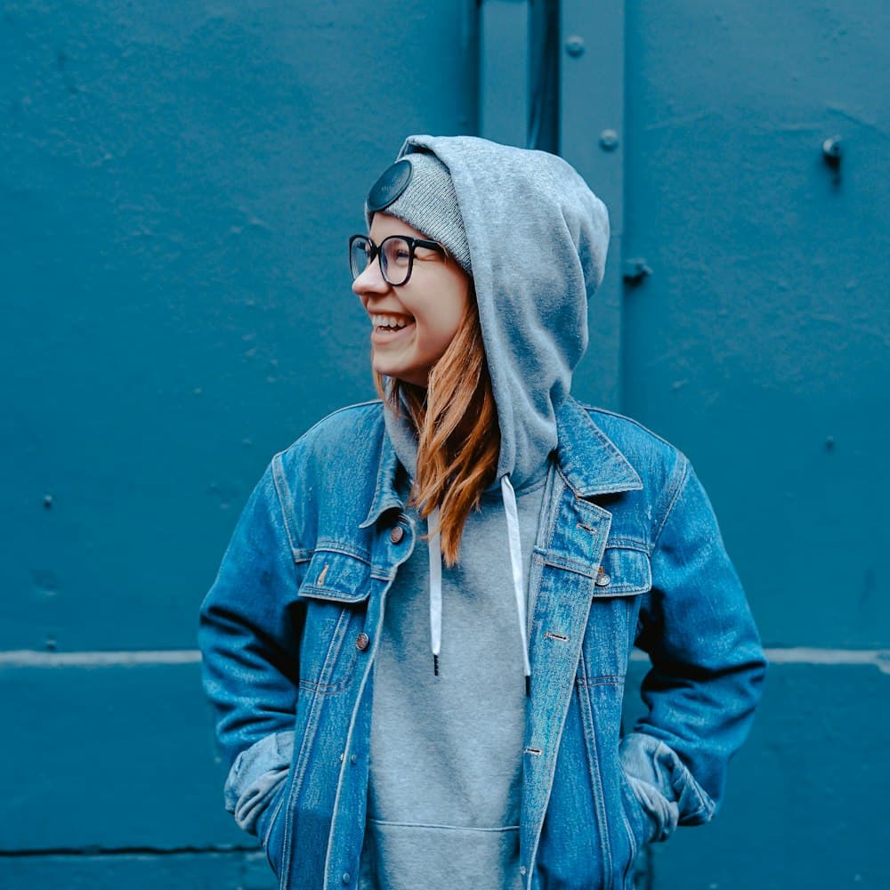 Young adult laughing, wearing glasses and a hoodie